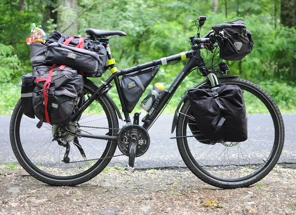 Foto eines Fahrrads, das mit Taschen hinten, vorn und am Lenker beladen ist