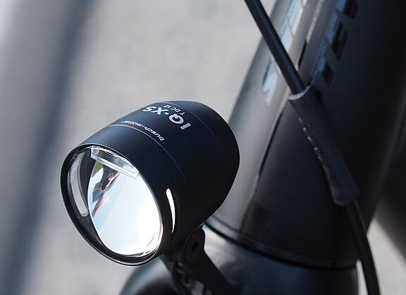 LED-Fahrradscheinwerfer Schwarzer LED-Fahrradscheinwerfer am silbernen Fahrradlenker montiert.