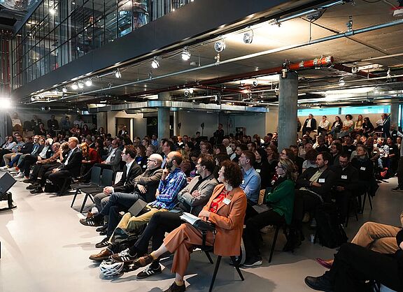 Ein Saal voller Menschen, die an der DB-Konferenz Anschluss erreichen teilnehmen.