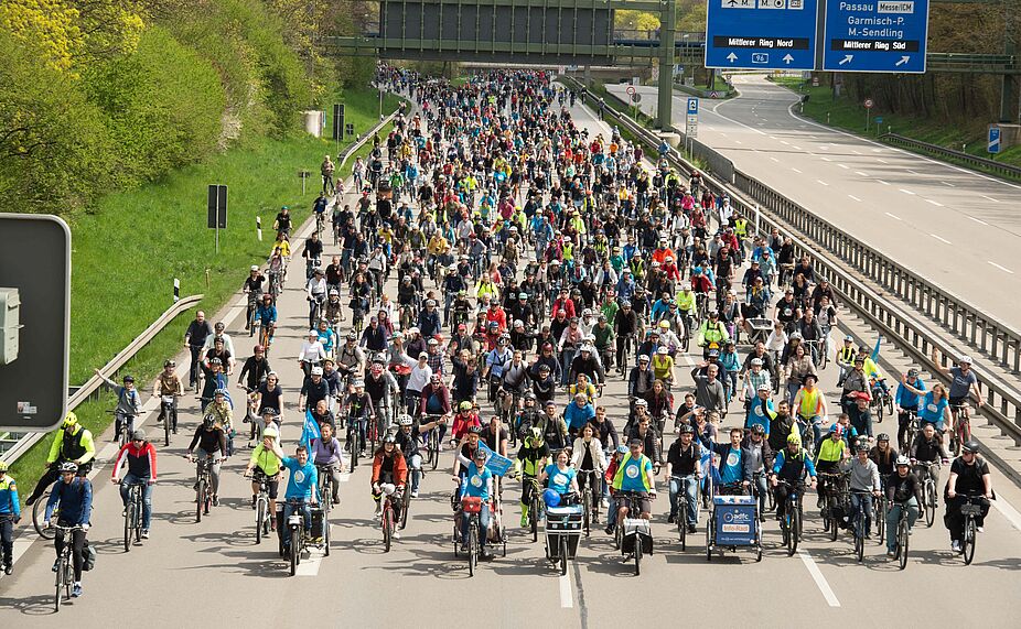 Teilnehmende der Münchner Sternfahrt 2023. Fernaufnahme einer Gruppe Radfahrender auf der Autobahn während der Sternfahrt in München.